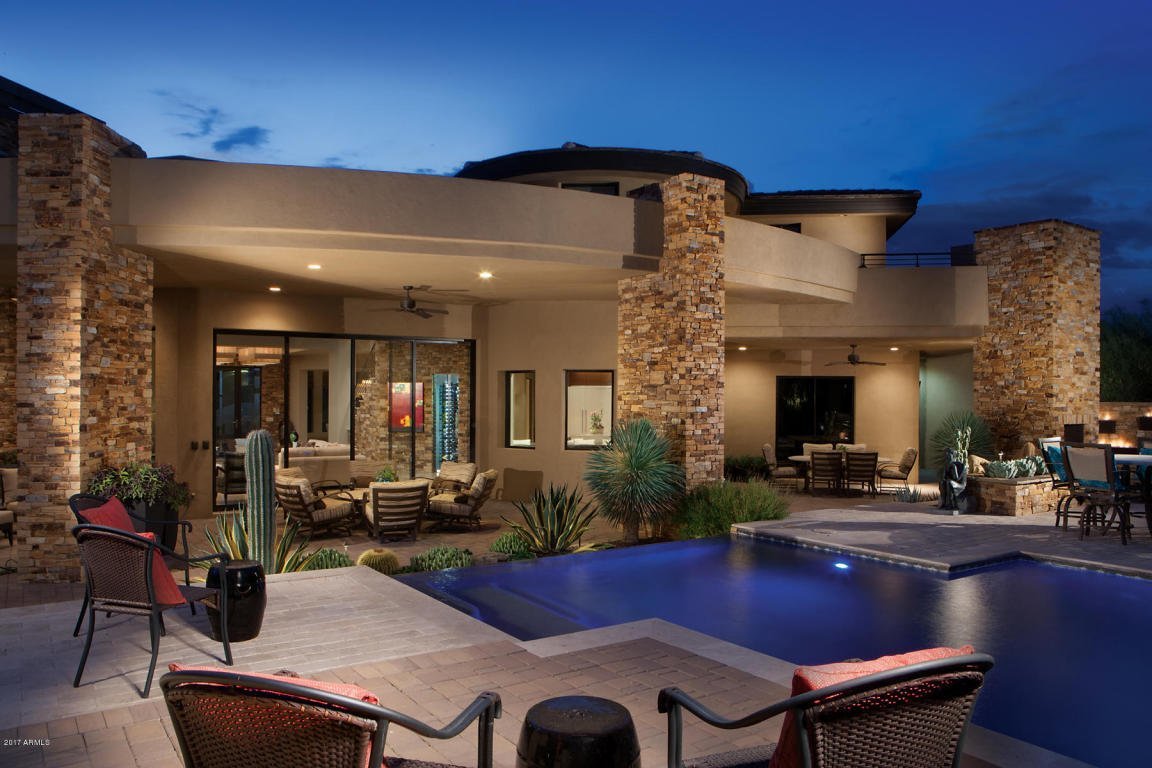 Luxury desert home, custom home, Southwestern architecture, contemporary architecture, stone exterior, stucco exterior, swimming pool, outdoor living spaces, twilight photography, Arizona real estate, resort-style living, high-end residential, custom home builder, outdoor entertainment, illuminated pool, dream home.