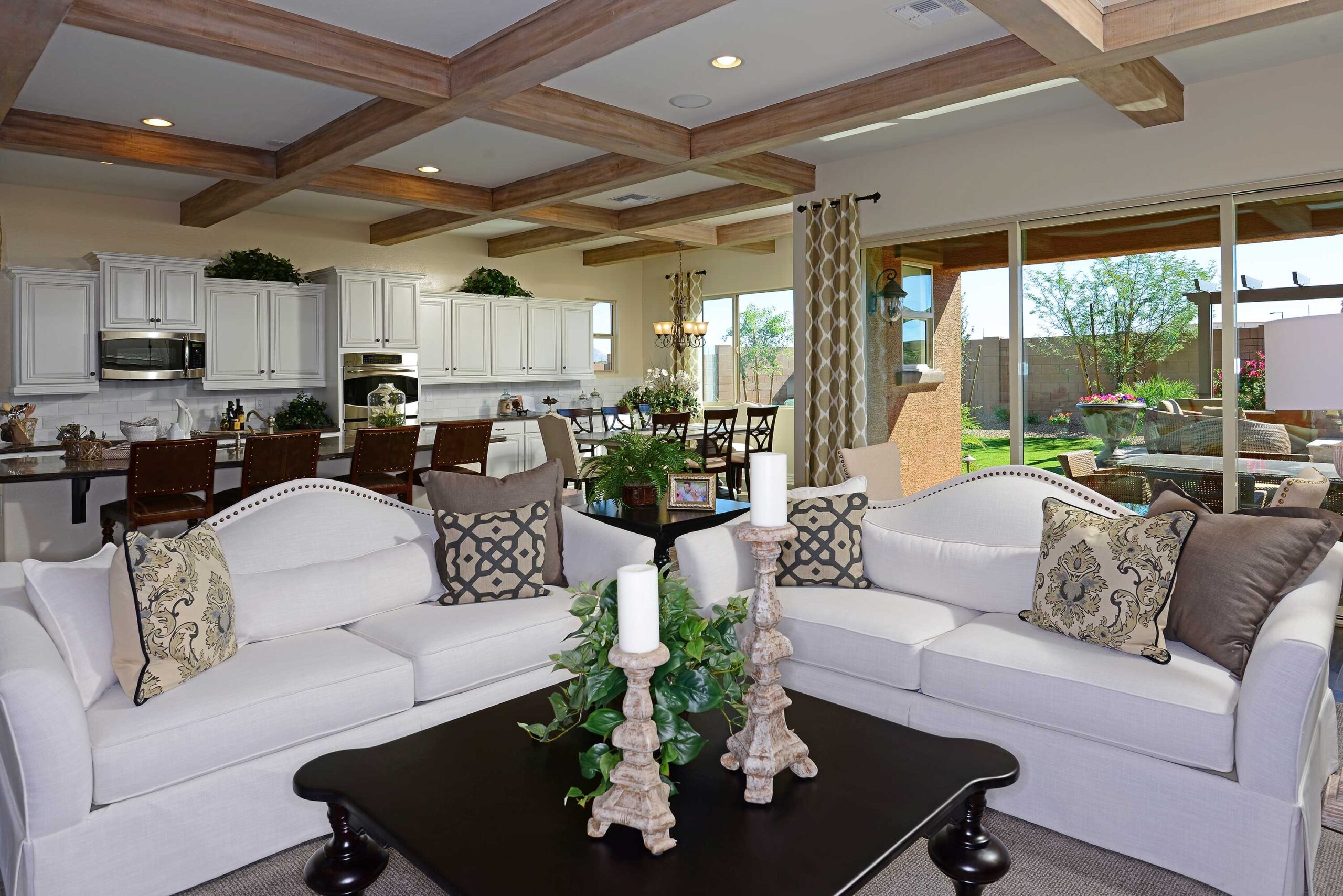 Open concept living, modern farmhouse style, contemporary home interior, living room design, kitchen view, exposed wood beams, white sectional sofa, light neutral decor, home staging, residential interior, custom built-ins, modern kitchen, stylish living space, indoor-outdoor living.