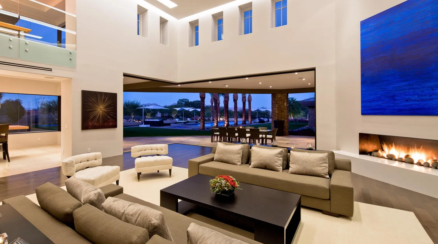 Luxury living room, modern interior design, high ceilings, linear fireplace, abstract art, indoor-outdoor living, sliding glass doors, backyard pool view, contemporary home, custom home interior, high-end residential, architectural design, open concept, entertainment space, dream home, desert modern.